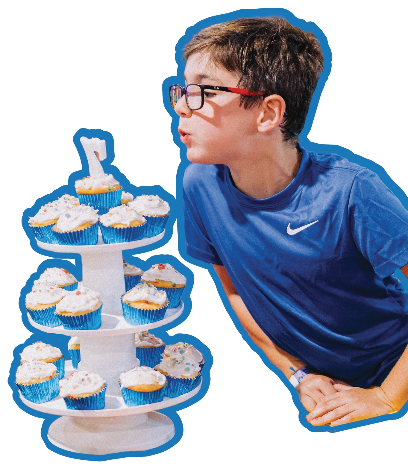 boy blowing out candle on cupcake tower